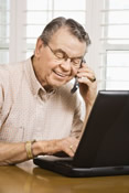 Senior citizen on phone at computer